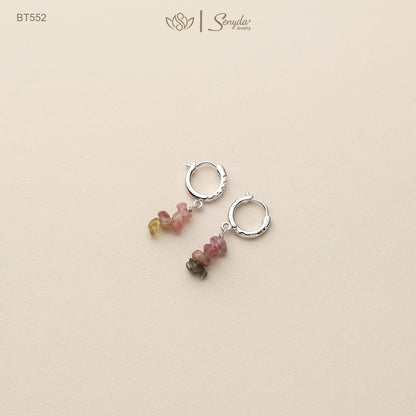 Pair of sterling silver huggie hoop earrings with pink, green and yellow tourmaline chip dangles on a beige background