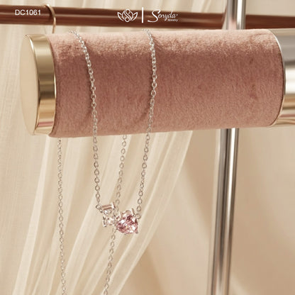 Dainty Toi et Moi necklace featuring a pastel pink heart gem paired with a clear emerald-cut cubic zirconia stone on a fine silver chain.