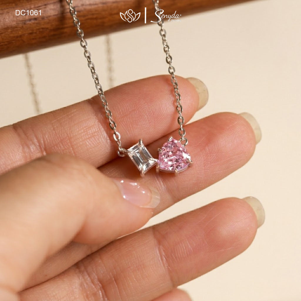 Dainty Toi et Moi necklace featuring a pastel pink heart gem paired with a clear emerald-cut cubic zirconia stone on a fine silver chain.