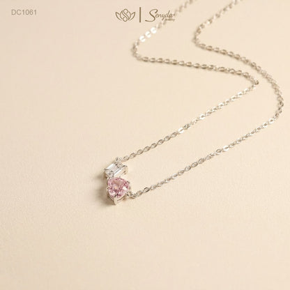 Dainty Toi et Moi necklace featuring a pastel pink heart gem paired with a clear emerald-cut cubic zirconia stone on a fine silver chain.
