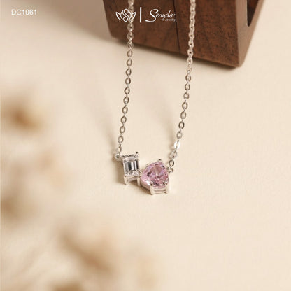 Dainty Toi et Moi necklace featuring a pastel pink heart gem paired with a clear emerald-cut cubic zirconia stone on a fine silver chain.