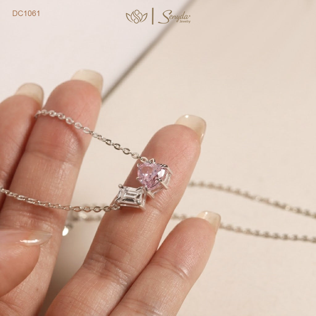 Dainty Toi et Moi necklace featuring a pastel pink heart gem paired with a clear emerald-cut cubic zirconia stone on a fine silver chain.