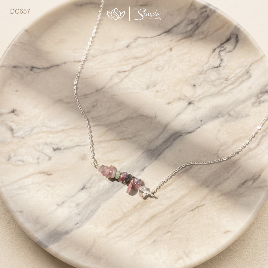 Sterling silver tourmaline chip bar necklace with pink, green and dark tourmaline stones on a white marble dish
