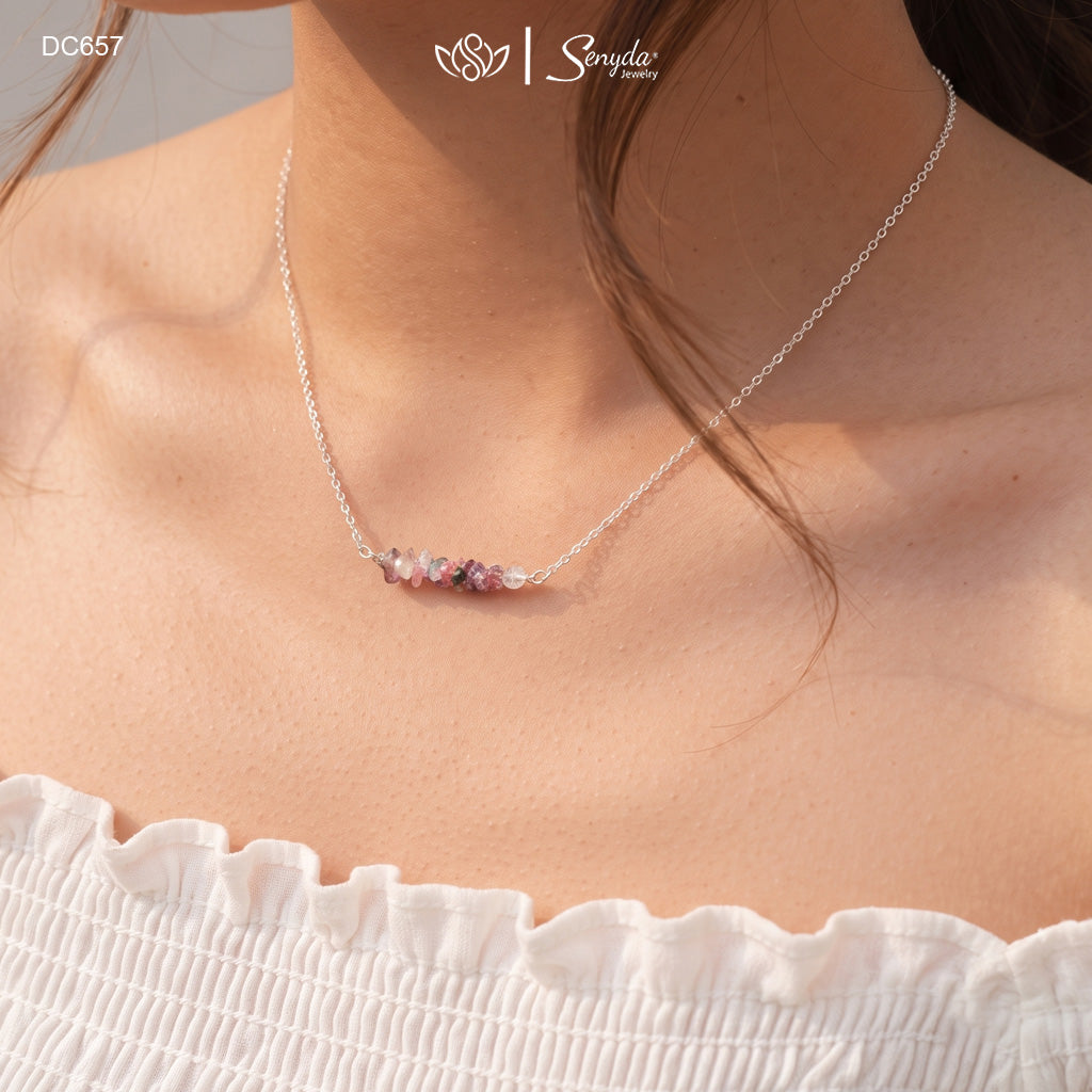 Woman wearing a dainty tourmaline chip bar necklace on a fine sterling silver chain at the collarbone