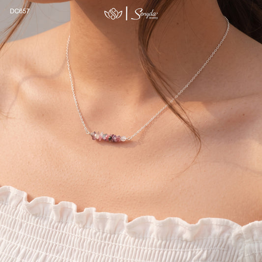 Woman wearing a dainty tourmaline chip bar necklace on a fine sterling silver chain at the collarbone
