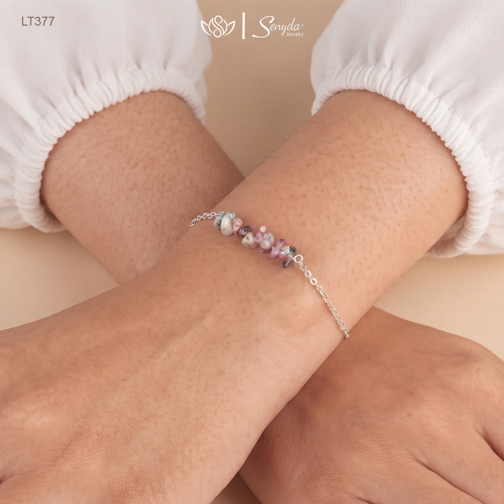 Woman wearing a dainty sterling silver bracelet with a bar of pink, green and gray tourmaline chips on her wrist