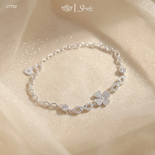 Sterling silver four leaf clover bracelet with pavé cubic zirconia heart leaves and infinity links on shimmering fabric