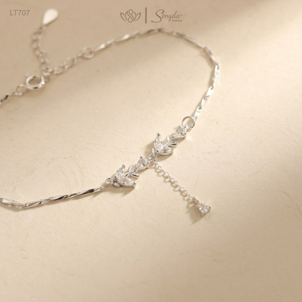 Sterling silver CZ leaf bracelet with teardrop dangle, spring ring clasp and extender chain on a cream background