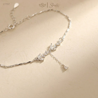 Sterling silver CZ leaf bracelet with teardrop dangle, spring ring clasp and extender chain on a cream background