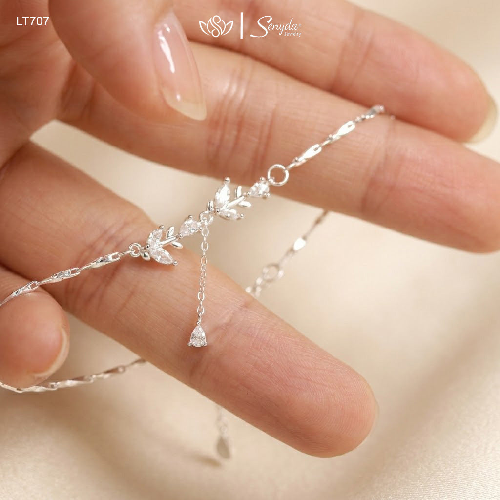 Hand holding a sterling silver leaf branch bracelet with marquise cubic zirconia leaves and a teardrop CZ dangle