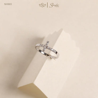 Sterling silver sideways cross ring with pavé cubic zirconia stones on a cream paper stand