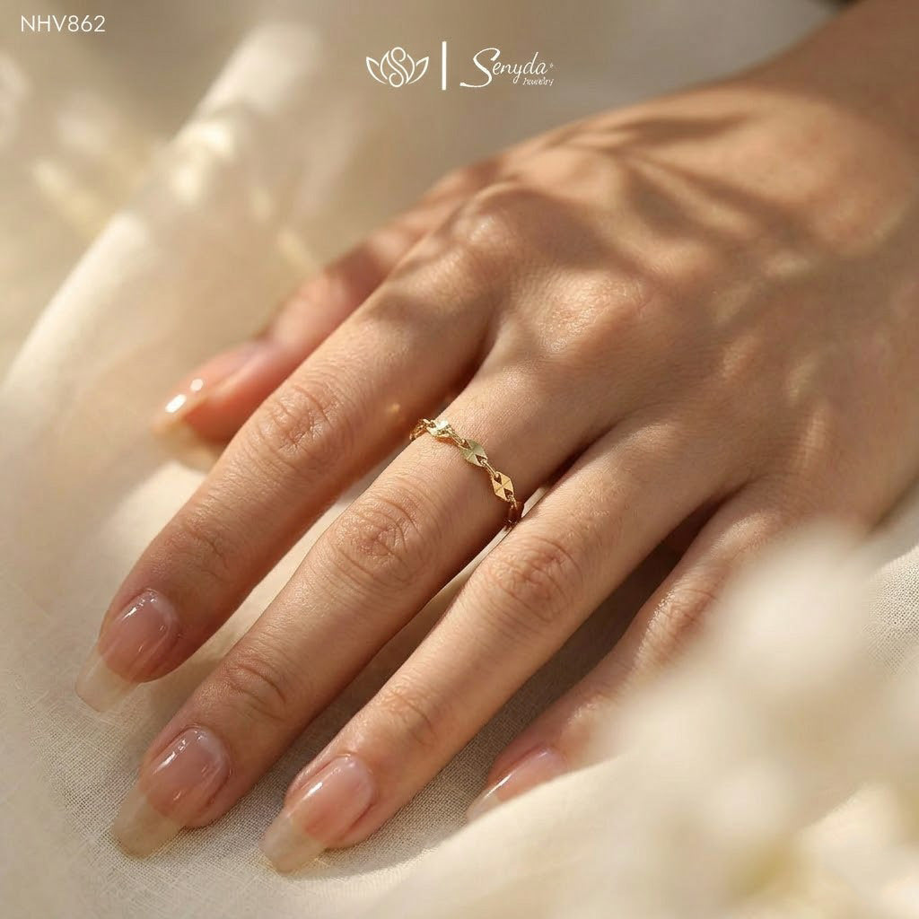 Dainty gold sequin chain ring featuring flat mirror disc links arranged in a flexible eternity loop on a wooden display.