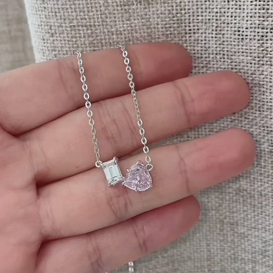 Dainty Toi et Moi necklace featuring a pastel pink heart gem paired with a clear emerald-cut cubic zirconia stone on a fine silver chain.